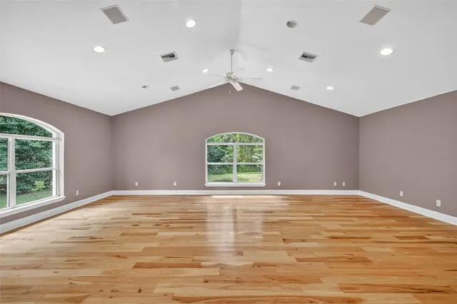 an empty room with windows and fan