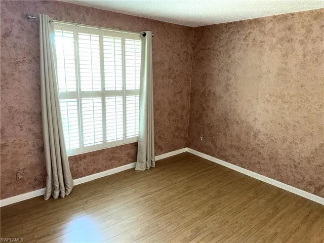 an empty room with wooden floor door and windows
