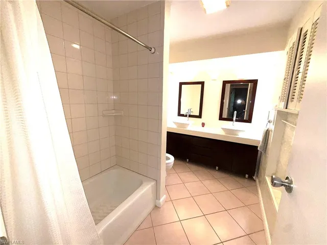 a bathroom with a double vanity sink toilet mirror and bathtub