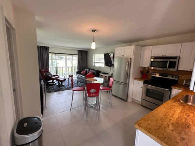a kitchen with stainless steel appliances granite countertop a refrigerator stove top oven dining table and chairs