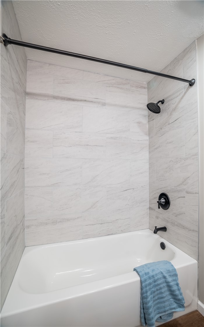 8240 Looney Road Piqua, OH 45356 - Photo 21 of 49 This modern bathroom features elegant tiled walls and a pristine tub, offering a clean and relaxing retreat.