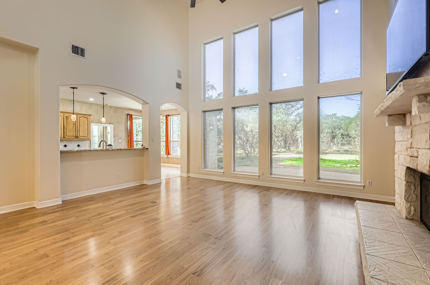 210 Amandas Way Leander, TX 78641 - Photo 5 of 38 Unfurnished living room featuring arched walkways, light wood finished floors, visible vents, a stone fireplace, and baseboards