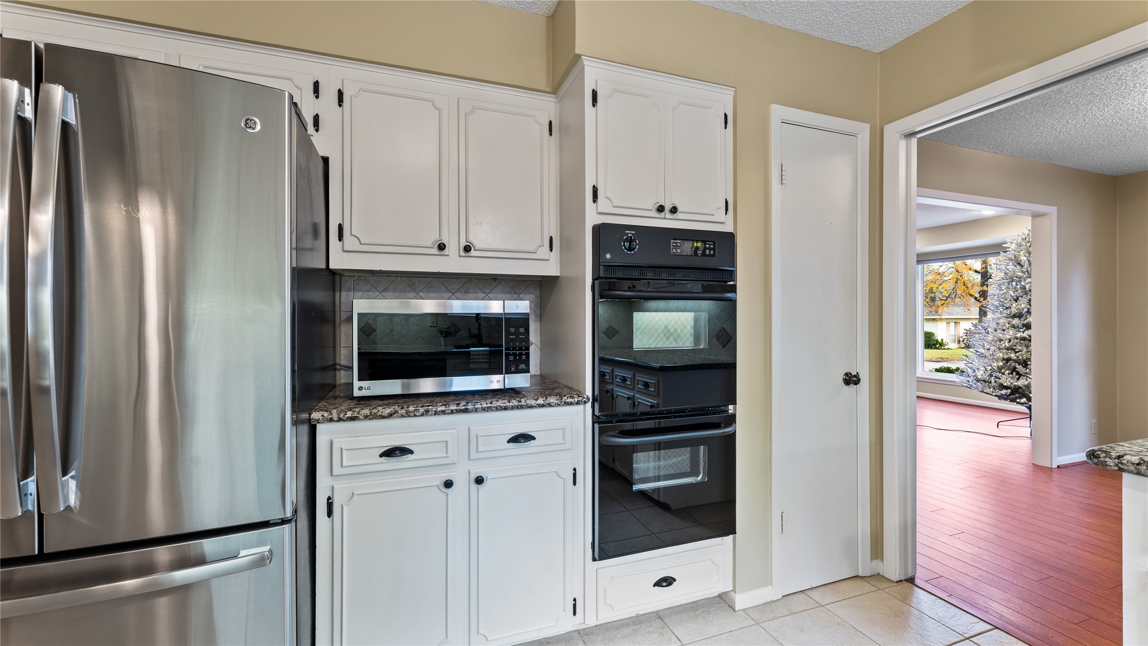 208 Magnolia Way Huntsville, TX 77320 - Photo 11 of 26 This kitchen features white cabinetry, granite countertops, and an updated tile backsplash. It includes a large double sink, electric cooktop, 2-built-in stoves, microwave, and a dishwasher. (Fridge is excluded from sale).