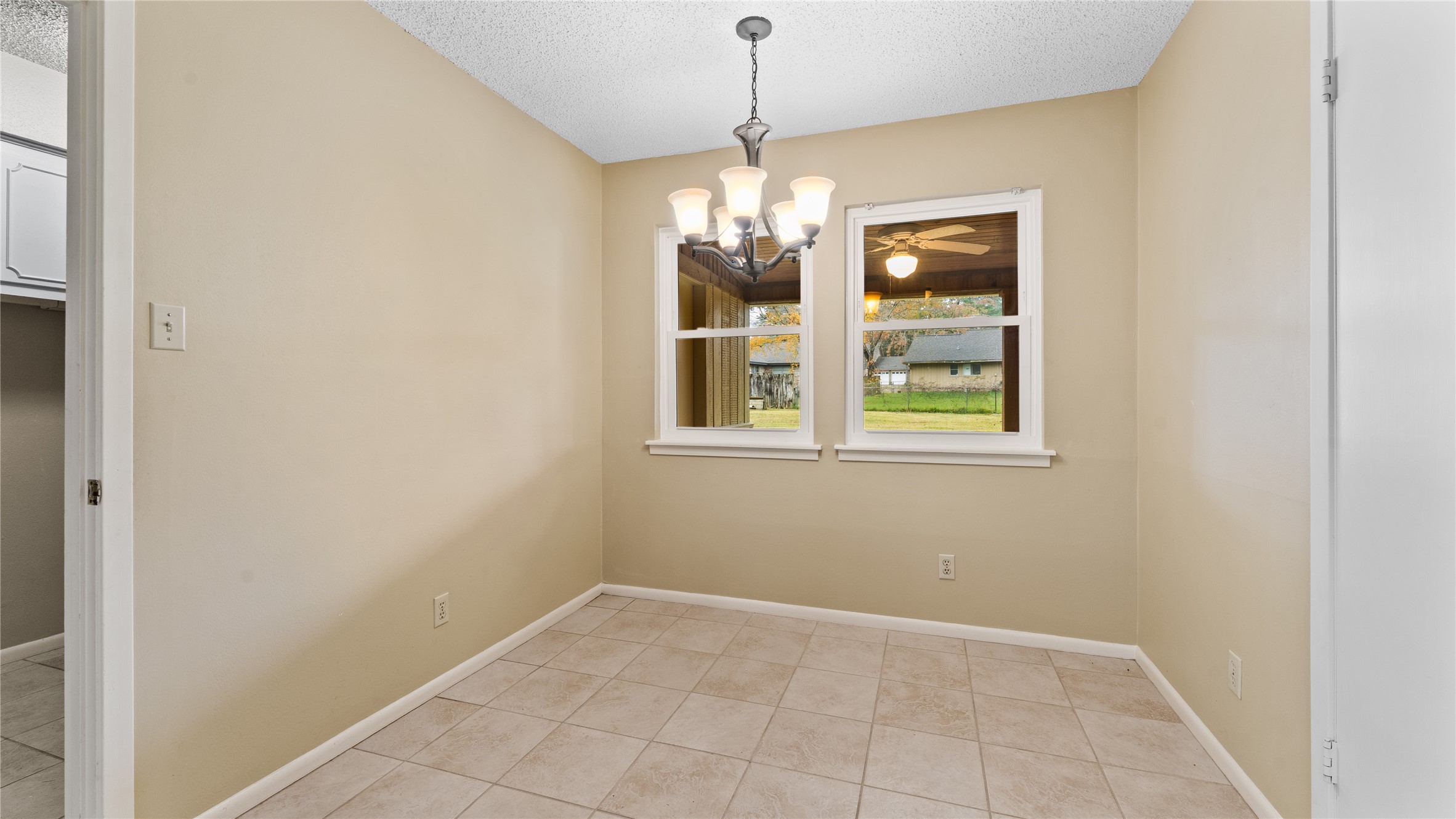 208 Magnolia Way Huntsville, TX 77320 - Photo 13 of 26 This breakfast area features neutral color tones, 2 pantries, and tiled flooring, with a central light fixture adding warmth. Two windows offer natural light and a view of the backyard, creating a welcoming space for meals.