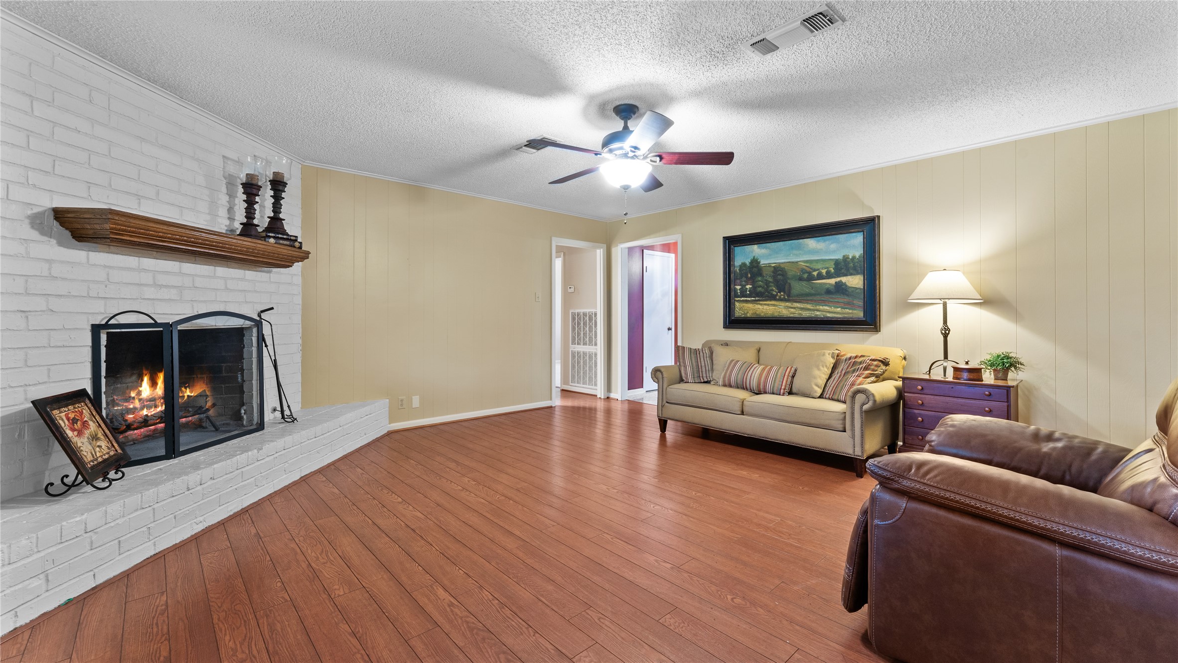 208 Magnolia Way Huntsville, TX 77320 - Photo 14 of 26 Looking for a living room that features warm wood floors and a wood burning fireplace. This living room is perfect for relaxing. It includes a ceiling fan, and soft lighting, creating an inviting area to relax.