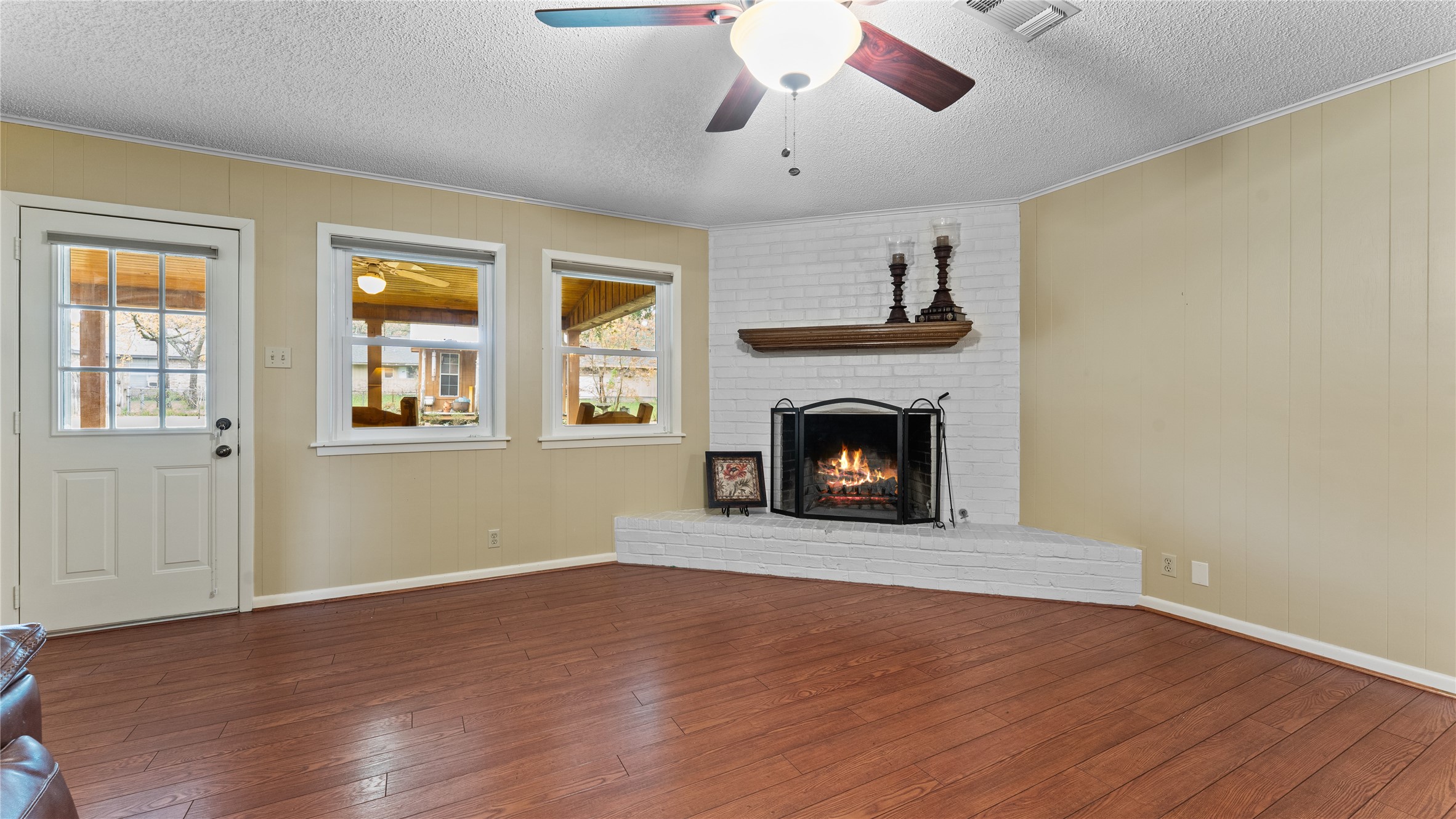 208 Magnolia Way Huntsville, TX 77320 - Photo 15 of 26 Looking for a living room that features warm wood floors and a wood burning fireplace. This living room is perfect for relaxing. It includes a ceiling fan, and soft lighting, creating an inviting area to relax.