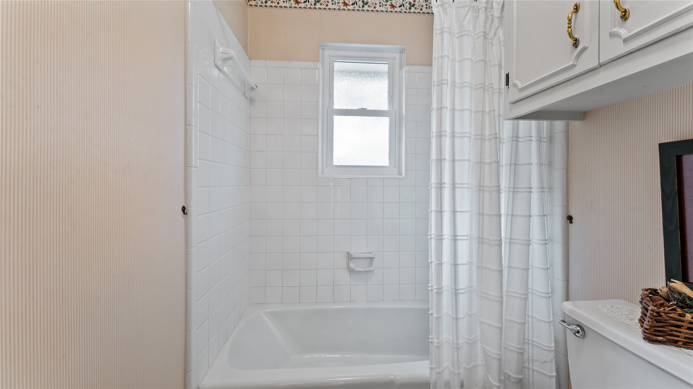 208 Magnolia Way Huntsville, TX 77320 - Photo 17 of 26 This bathroom features a classic white tiled bathtub with shower head, new windows for natural light, and built-in storage cabinets.