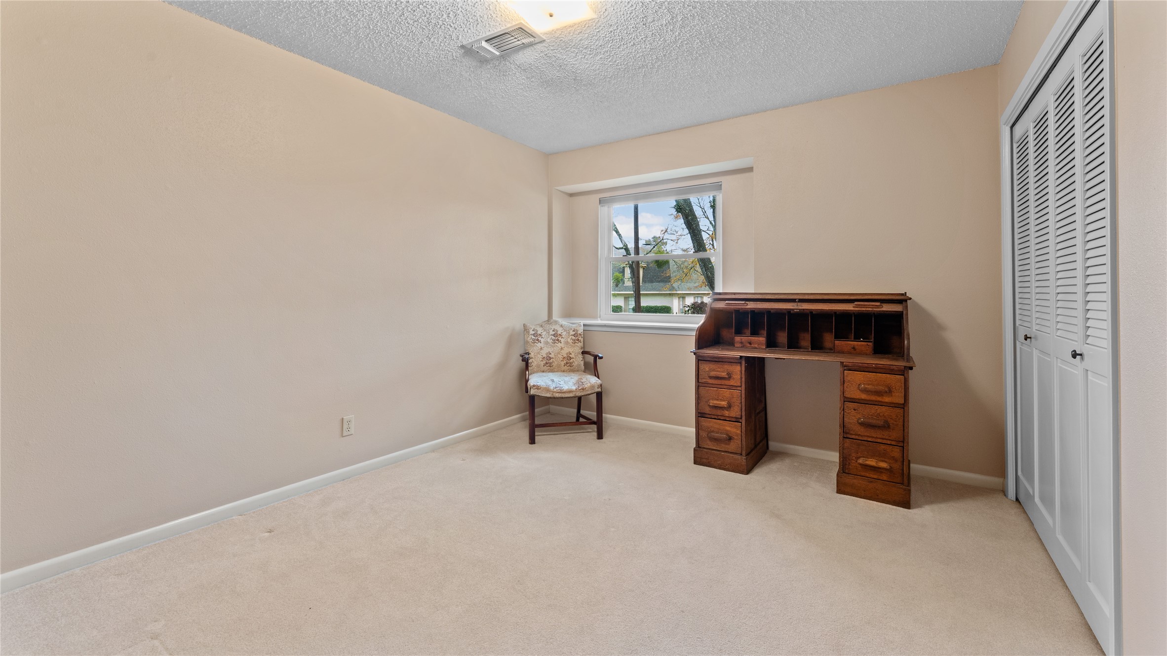 208 Magnolia Way Huntsville, TX 77320 - Photo 18 of 26 This room features neutral walls and carpet, a window for natural light, and a closet with sliding doors.