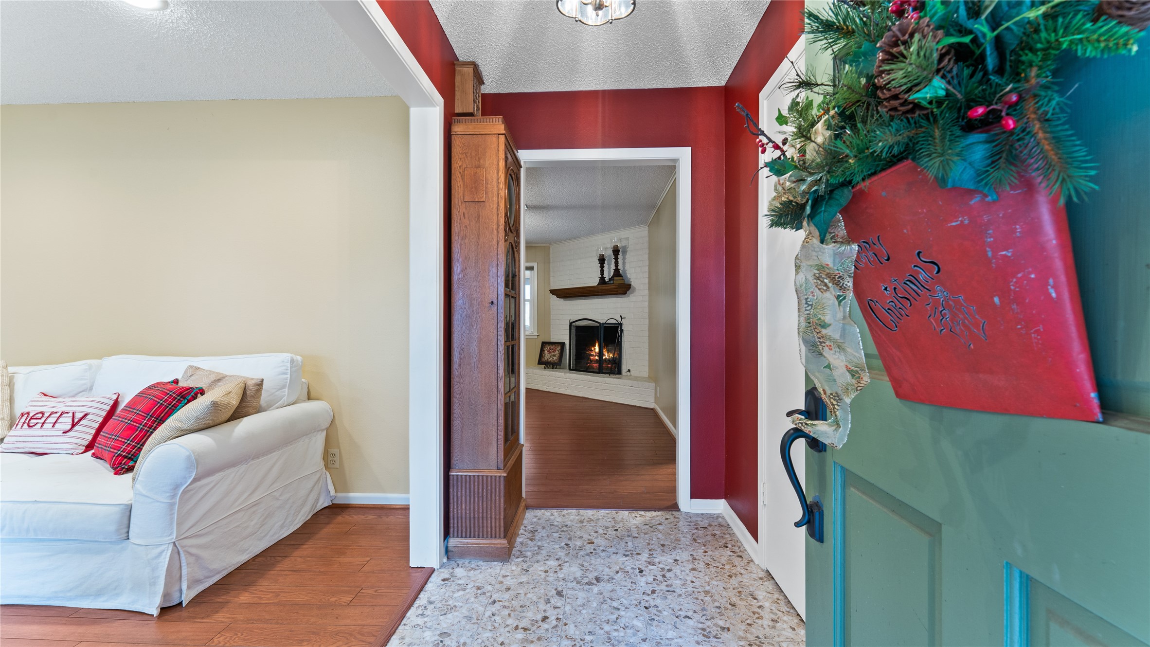 208 Magnolia Way Huntsville, TX 77320 - Photo 5 of 26 Warm and inviting entryway with holiday decor, leading to a cozy living area featuring a fireplace. The space has a welcoming atmosphere with a mix of soft and rich colors, hardwood floors, and comfortable seating.