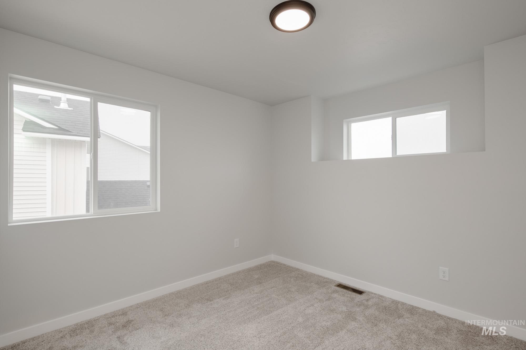2391 West Fallon Loop Nampa, ID 83651 - Photo 12 of 20 Carpeted interior space featuring neutral wall tones, white trim, and a contemporary flush-mount ceiling light fixture