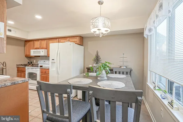 a kitchen with stainless steel appliances a dining table chairs and refrigerator