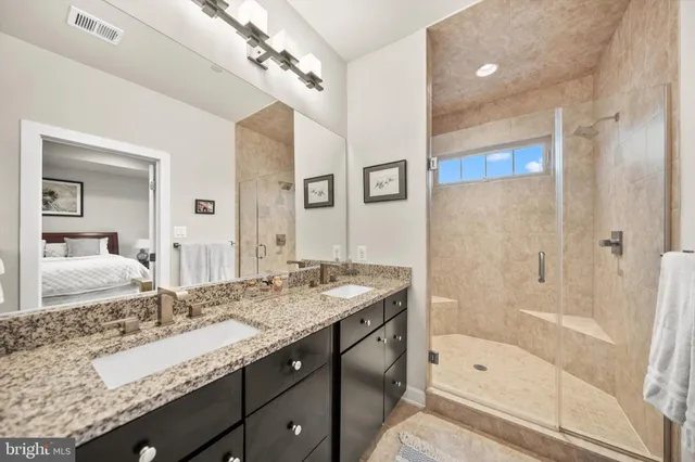 a bathroom with a granite countertop sink a mirror a bathtub and shower