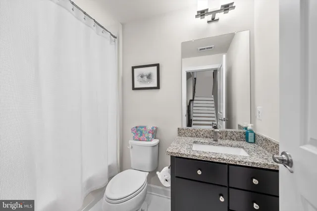 a bathroom with a granite countertop sink mirror vanity and toilet