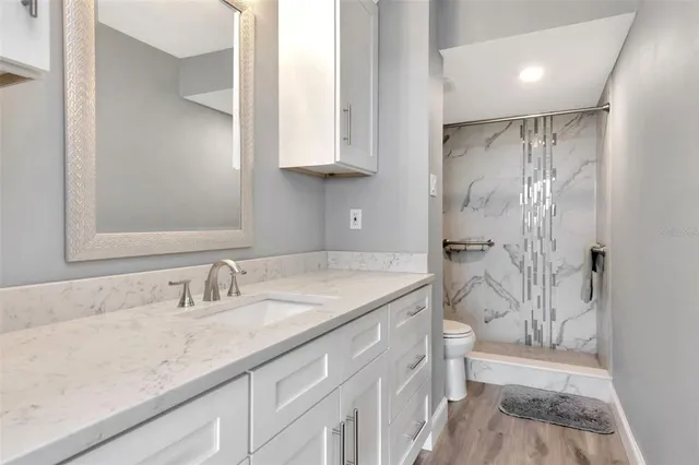 a bathroom with a granite countertop sink a mirror and a shower