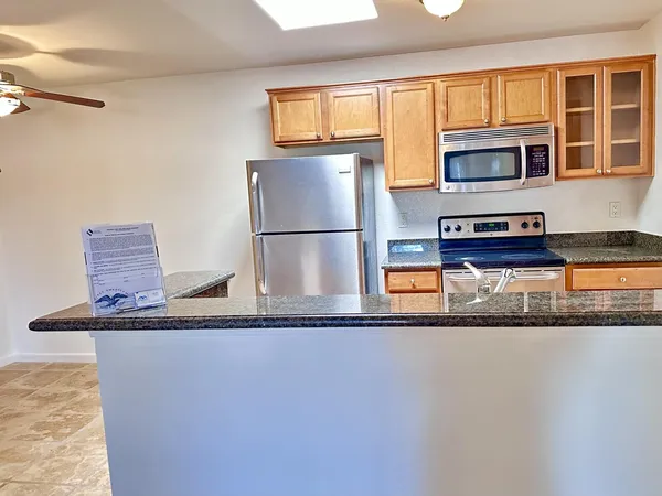 a kitchen with stainless steel appliances granite countertop a refrigerator a stove and a sink with wooden floor