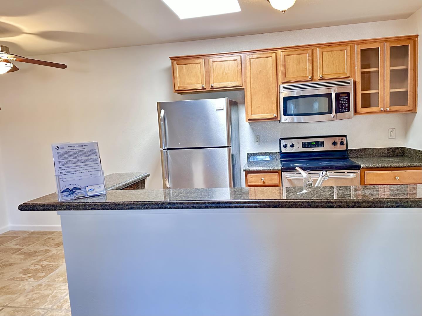 a kitchen with stainless steel appliances granite countertop a refrigerator a stove and a sink with wooden floor