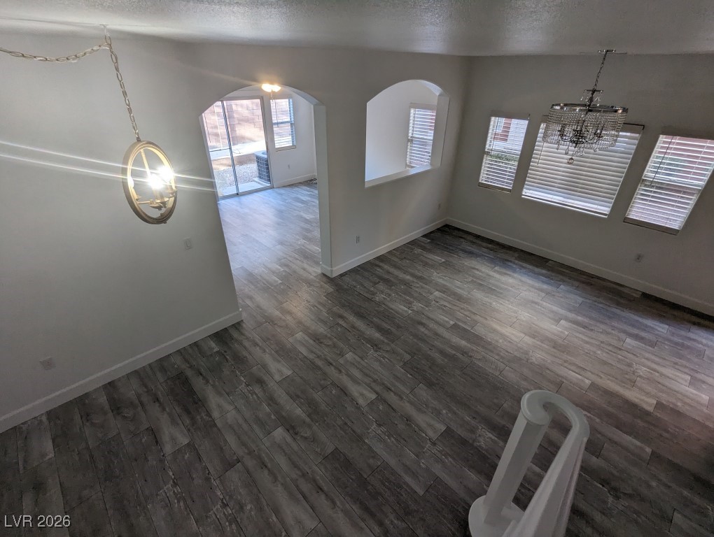 9303 Gilcrease Avenue, Unit 1137 Las Vegas, NV 89149 - Photo 13 of 30 Unfurnished dining area with a textured ceiling, dark wood-type flooring, and a chandelier
