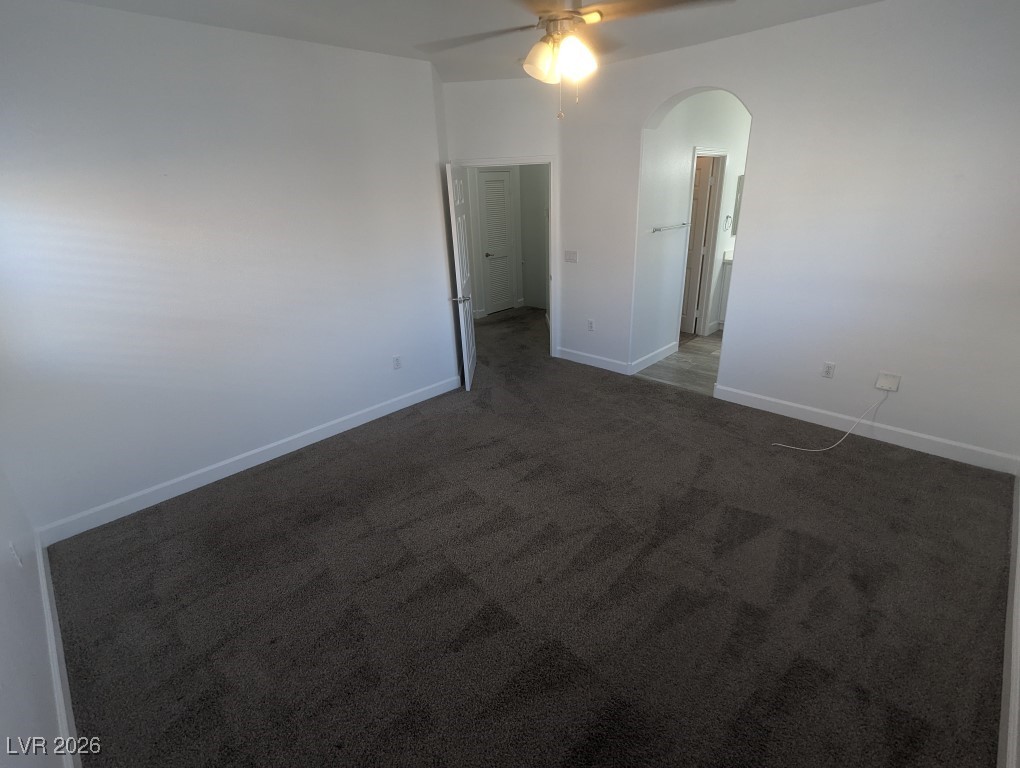 9303 Gilcrease Avenue, Unit 1137 Las Vegas, NV 89149 - Photo 18 of 30 Empty room featuring dark carpet, arched walkways, and ceiling fan