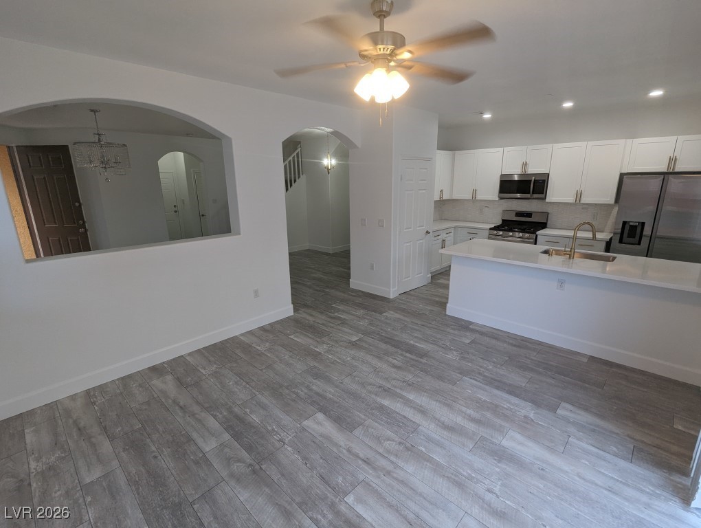9303 Gilcrease Avenue, Unit 1137 Las Vegas, NV 89149 - Photo 6 of 30 Kitchen with white cabinets, appliances with stainless steel finishes, backsplash, light wood-style floors, and light stone counters