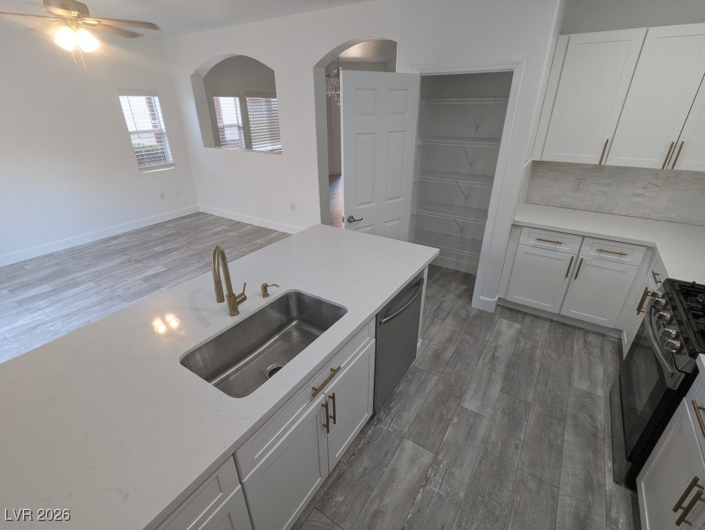 9303 Gilcrease Avenue, Unit 1137 Las Vegas, NV 89149 - Photo 10 of 30 Kitchen with white cabinetry, light wood-style flooring, decorative backsplash, and light stone countertops