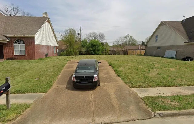 a car parked in front of a house with a yard