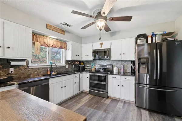 a kitchen with granite countertop a sink and dishwasher a stove with wooden floors