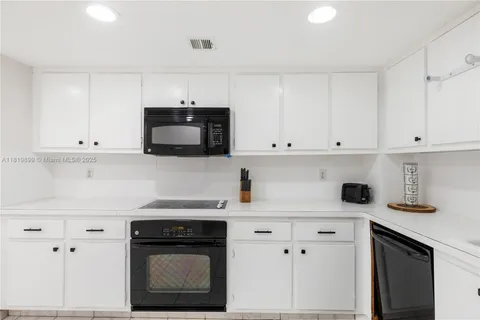 a kitchen with white cabinets and black appliances