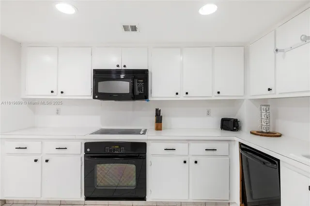 a kitchen with white cabinets and black appliances