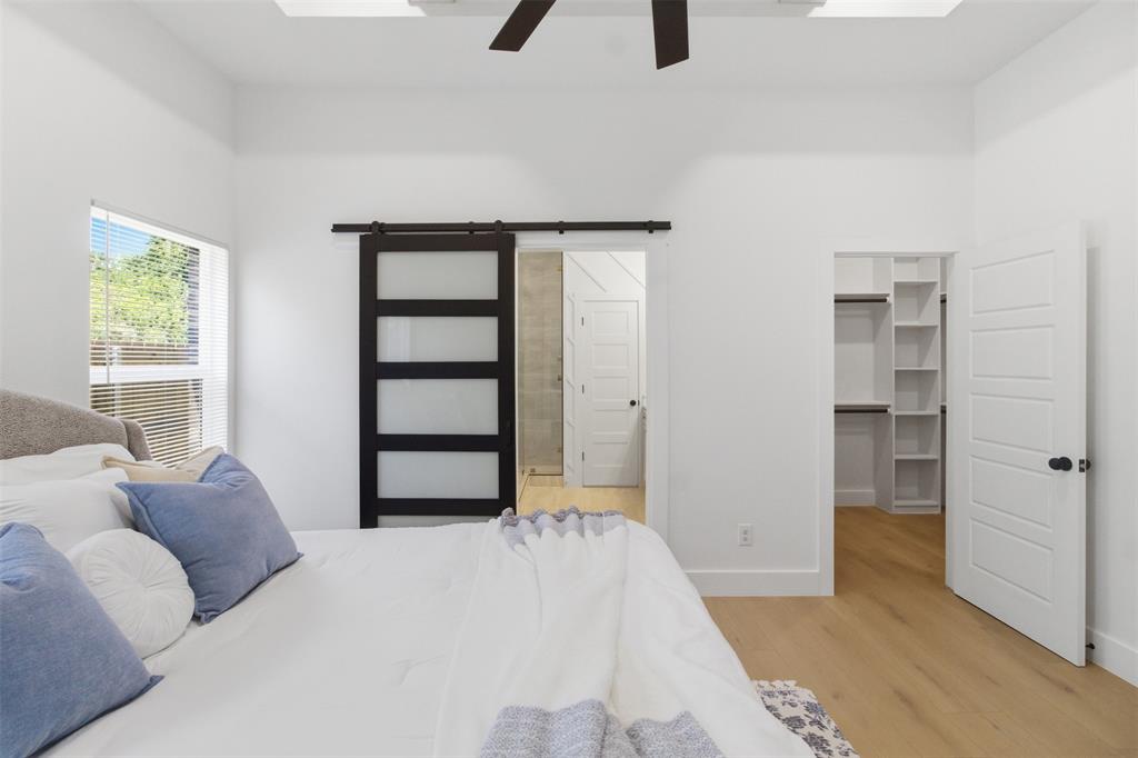 435 Waterboard Road Trinidad, TX 75163 - Photo 25 of 39 Vaulted ceiling featuring a ceiling fan, light wood-finish flooring, a sliding barn door with frosted glass panels, and an organized closet with shelving and hanging rods