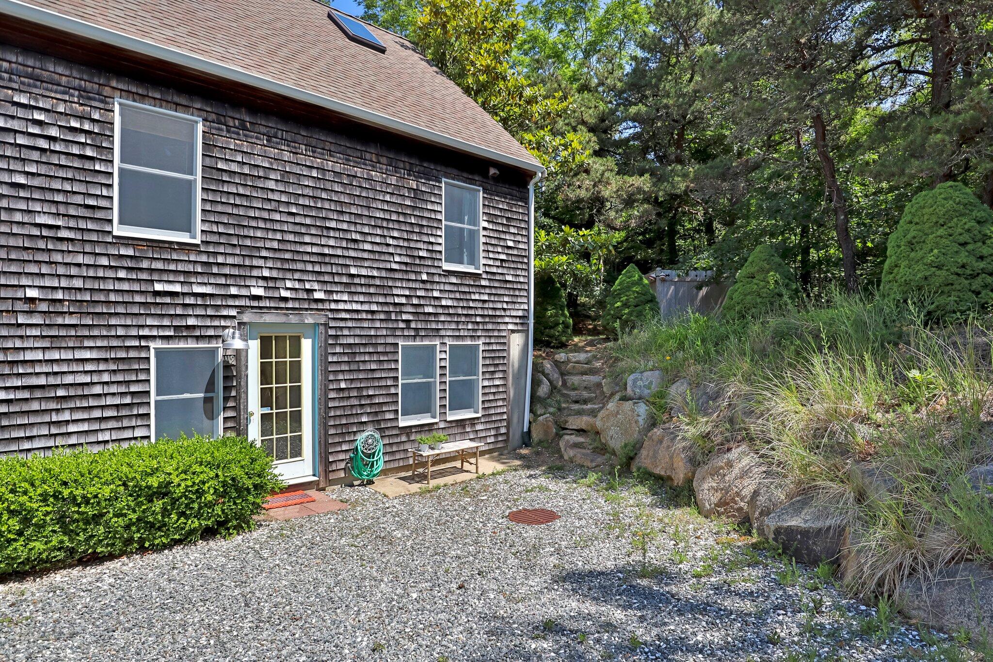 112 Castle Road Truro, MA 02666 - Photo 6 of 43 a brick house with a yard plants and large tree