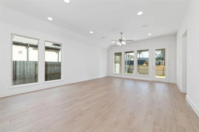 a view of an empty room with a window and wooden floor