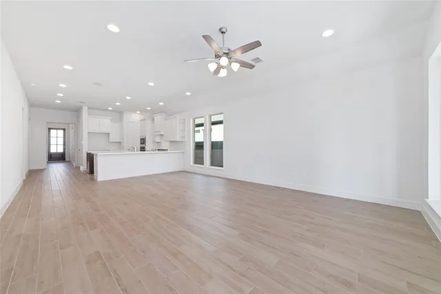 a view of a livingroom with a kitchen island stainless steel appliances wooden floor and a chandelier