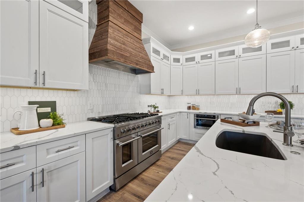 a kitchen with stainless steel appliances a stove a sink and white cabinets
