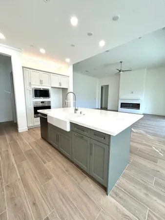 a large white kitchen with wooden floor and stainless steel appliances