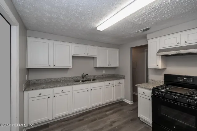 a kitchen with granite countertop white cabinets and stainless steel appliances