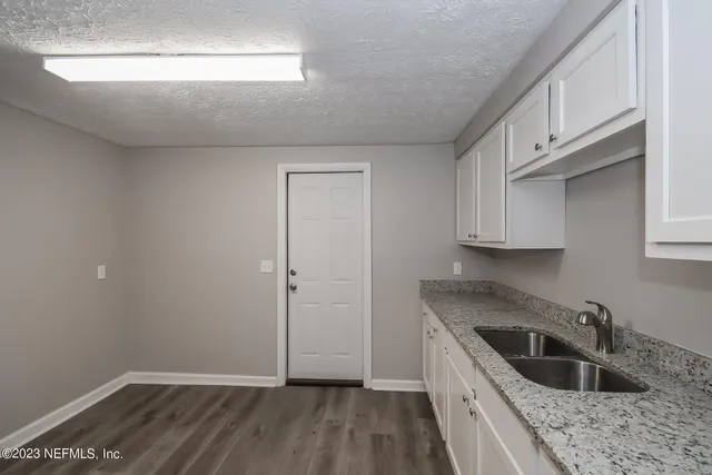 a kitchen with granite countertop a sink a stove and cabinets