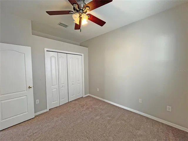 an empty room with closet and a chandelier fan