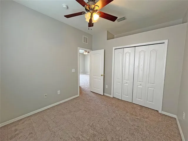 an empty room with closet and a chandelier fan