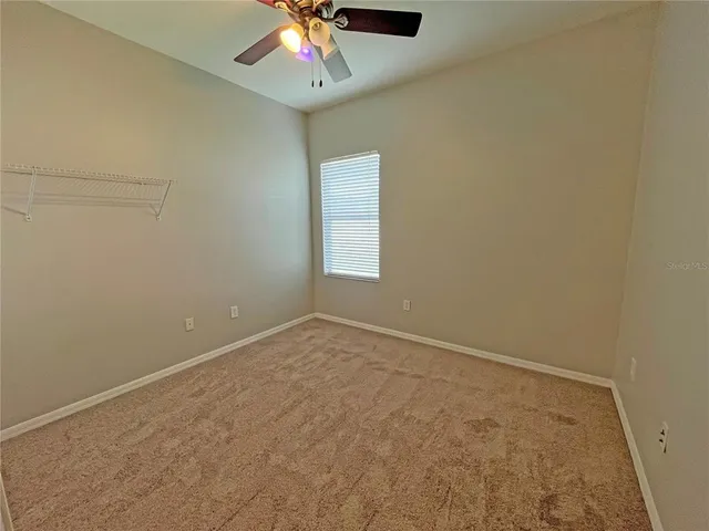 an empty room with a ceiling fan and window