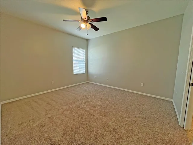 an empty room with a ceiling fan and carpet