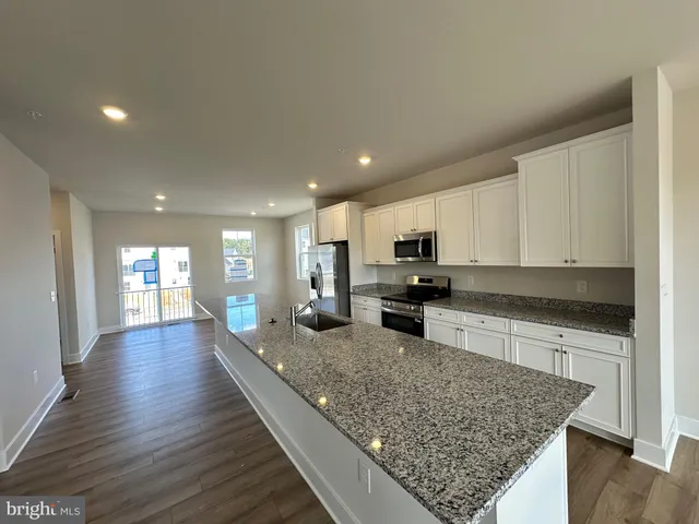 a large kitchen with stainless steel appliances granite countertop a large counter top and wooden floor