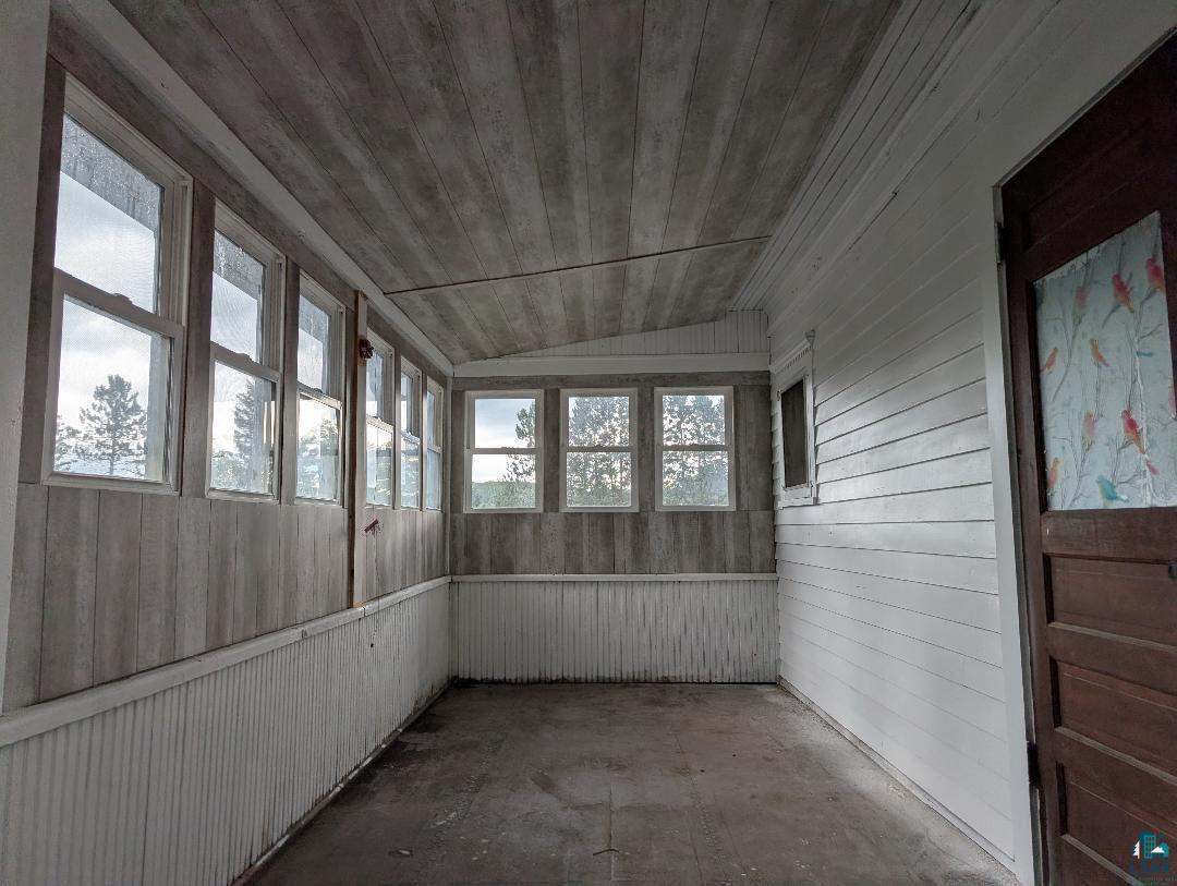202 Thomas Street Mellen, WI 54546 - Photo 22 of 37 Enclosed porch with multiple windows, wood-finish paneling, white horizontal siding, and a paneled wood door
