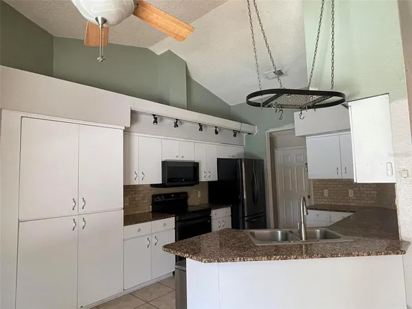 a kitchen with stainless steel appliances granite countertop a refrigerator a stove and a sink