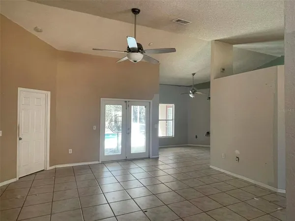 a view of an empty room with window and chandelier fan
