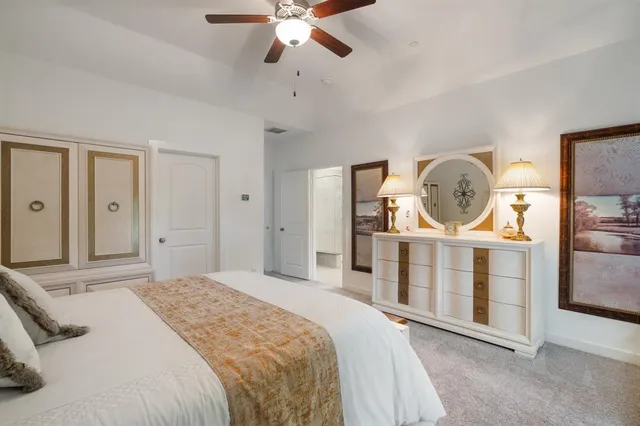 a bedroom with a bed a mirror on the dresser and a chandelier