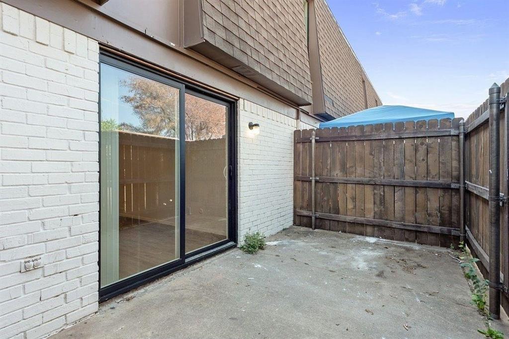 7700 Chapin Road, Unit 5 Fort Worth, TX 76116 - Photo 11 of 12 Private patio with concrete surfacing, white brick exterior, black-framed sliding glass door, and wood privacy fencing