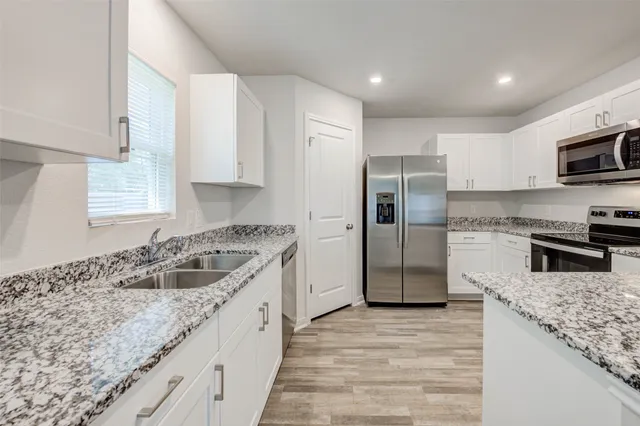 a kitchen with granite countertop a sink stove and refrigerator