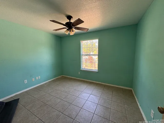 an empty room with a window and a fan