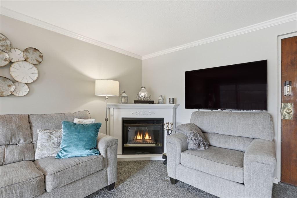 68 Main Street, Unit 36C Stoneham, MA 02180 - Photo 5 of 19 a living room with furniture a flat screen tv and a fireplace