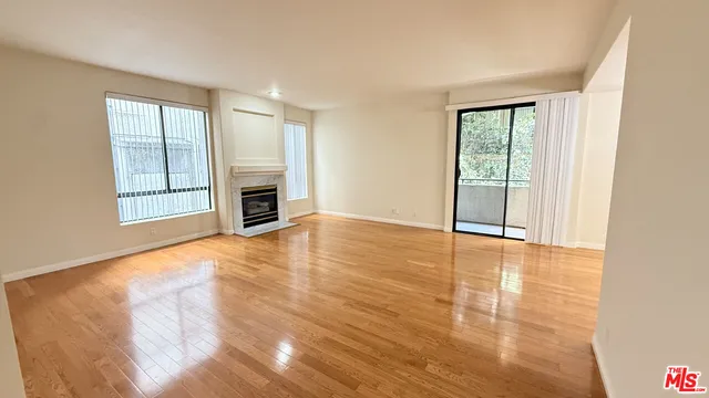 a view of empty room with wooden floor and fireplace